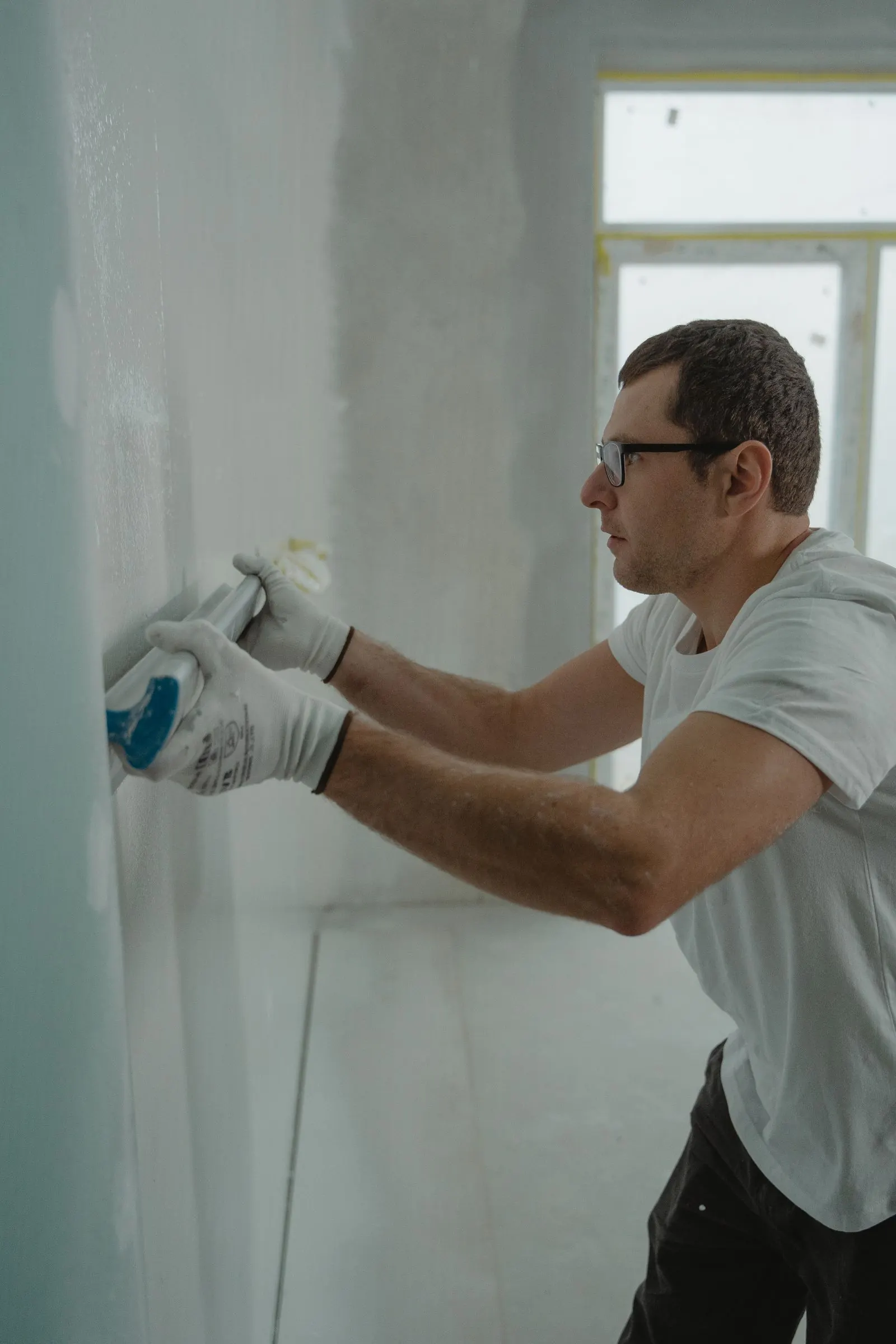 Worker in gloves prepping an interior wall for painting