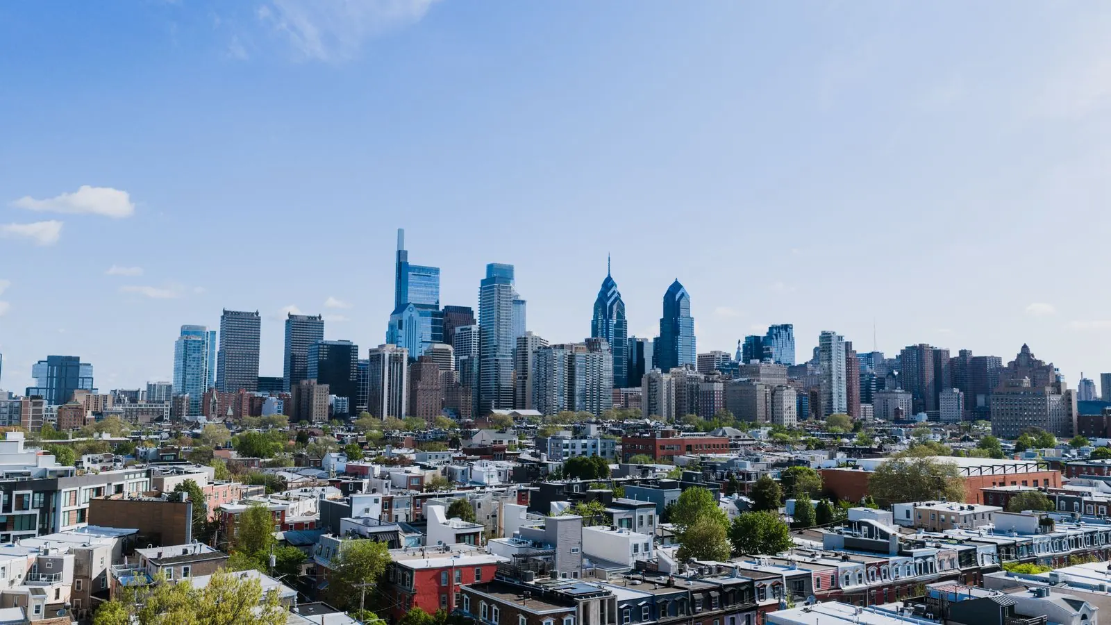 Philadelphia skyline rising above residential neighborhoods on a sunny day
