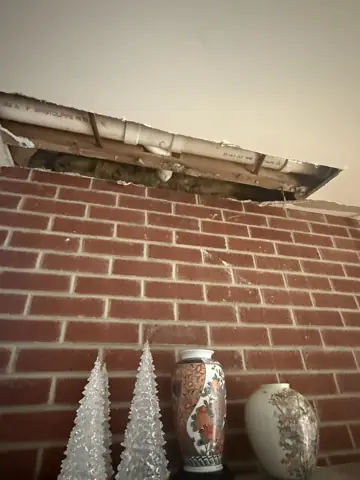 Exposed brick wall with a ceiling soffit repair in progress