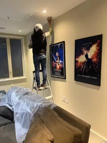 Installing a ceiling fixture on a ladder in a living room
