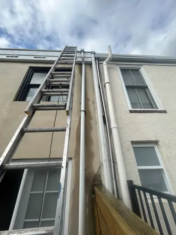 Ladder set up against a Philadelphia rowhome for roof and gutter work