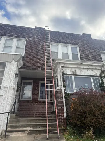 Ladder set up on a Philadelphia rowhome for roof and second-floor exterior repairs