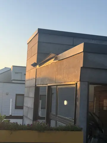 Modern rowhome exterior with a rear deck at dusk