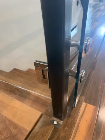 New black stair railing post installed on hardwood stairs