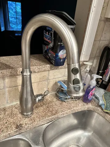 New brushed nickel kitchen faucet installed over a stainless sink