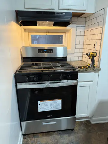 New stainless steel range and hood installed in a renovated kitchen