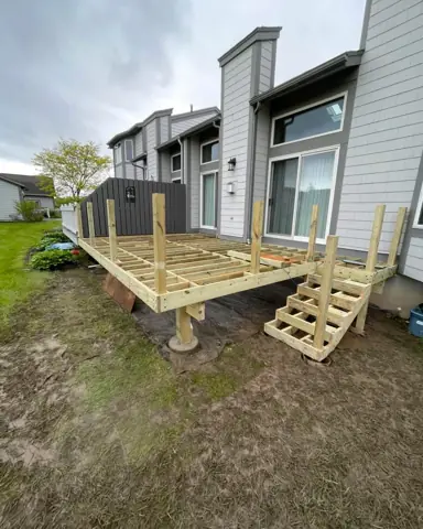 New wood deck with steps built behind a home