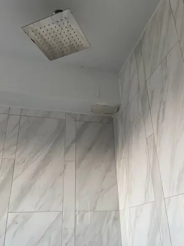 Newly tiled shower walls with a rain shower head
