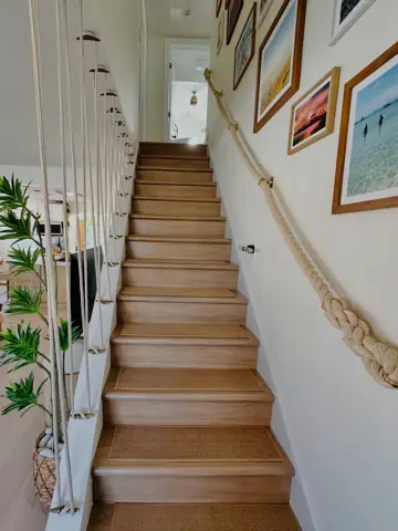 Refinished hardwood staircase with a rope handrail in a rowhome