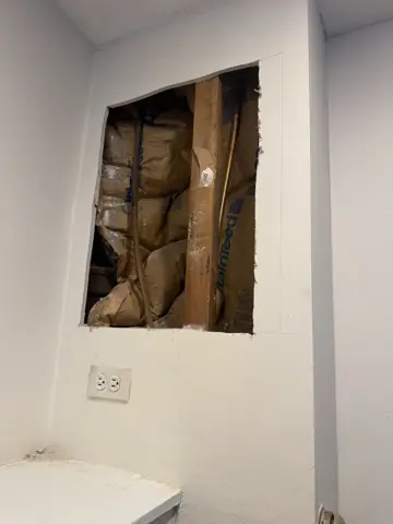 Square section of damaged drywall cut out to inspect a leak behind the wall