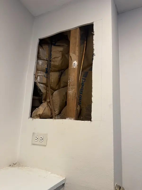 Square section of damaged drywall cut out to inspect a leak behind the wall