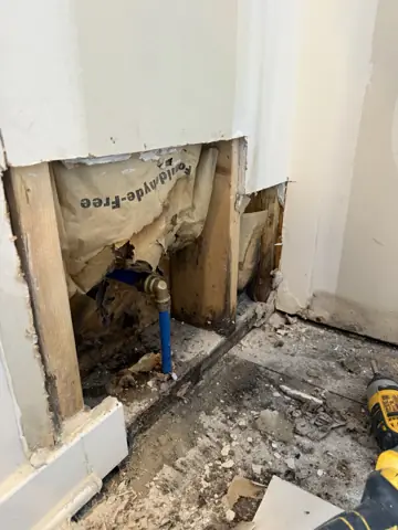 Water-damaged wall opened down to the framing near the floor