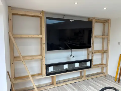 Wood-framed built-in around a wall-mounted TV under construction